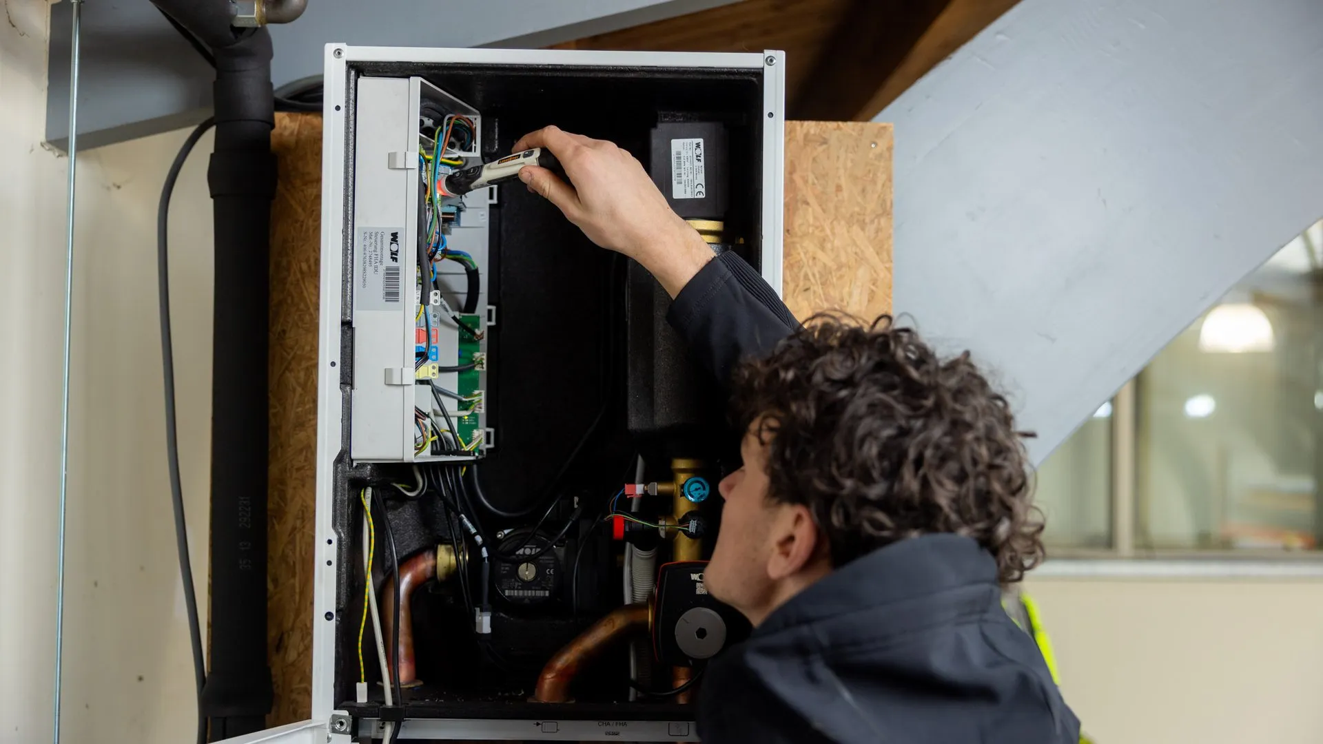 Monteur inspecteert binnenkant van warmtepomp of cv-installatie