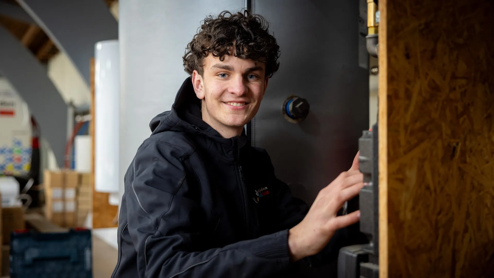 Lachende installatiemonteur naast warmtepomp-unit in werkplaats