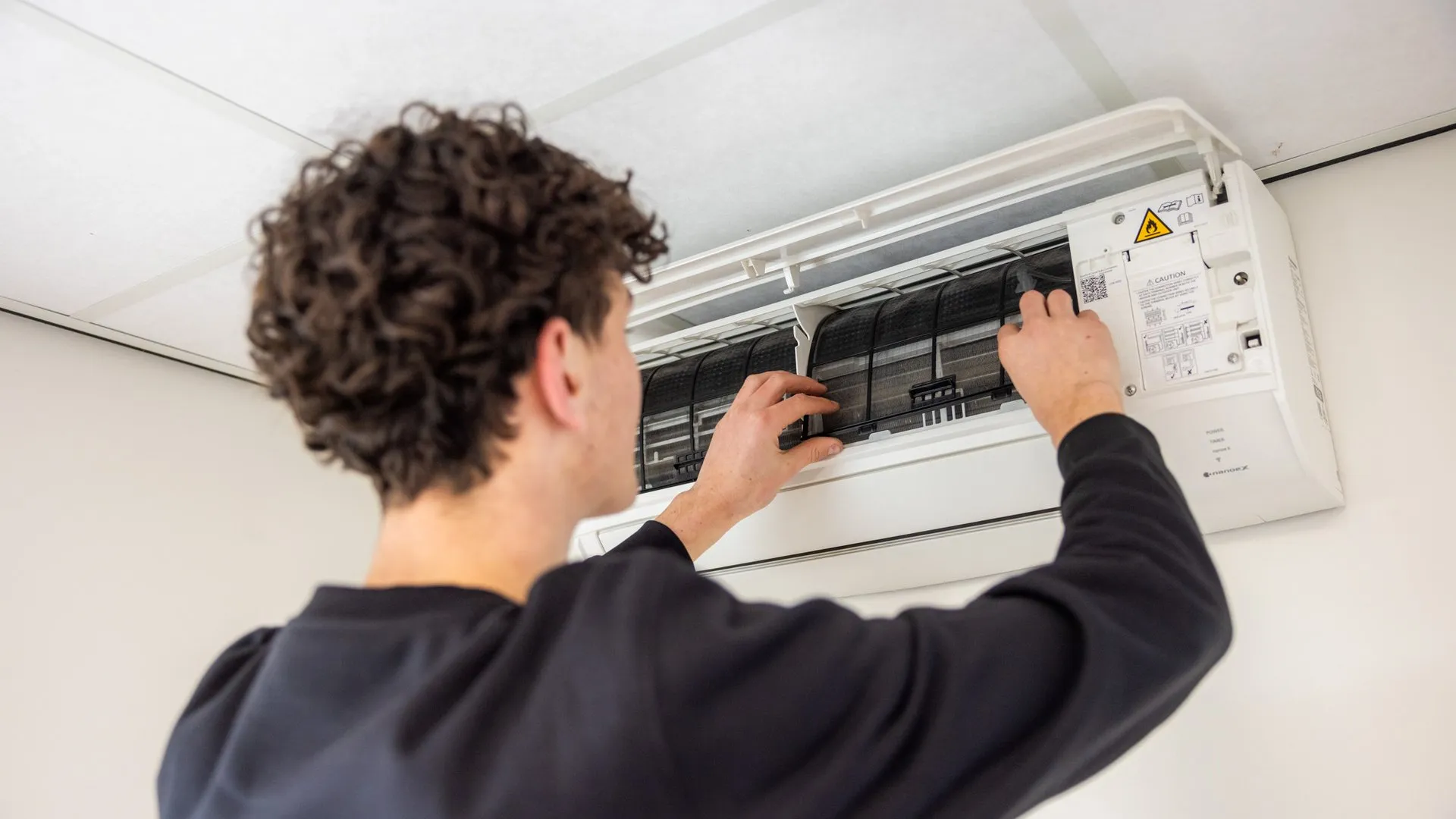 Monteur reinigt binnenkant van airco binnenunit tijdens onderhoud