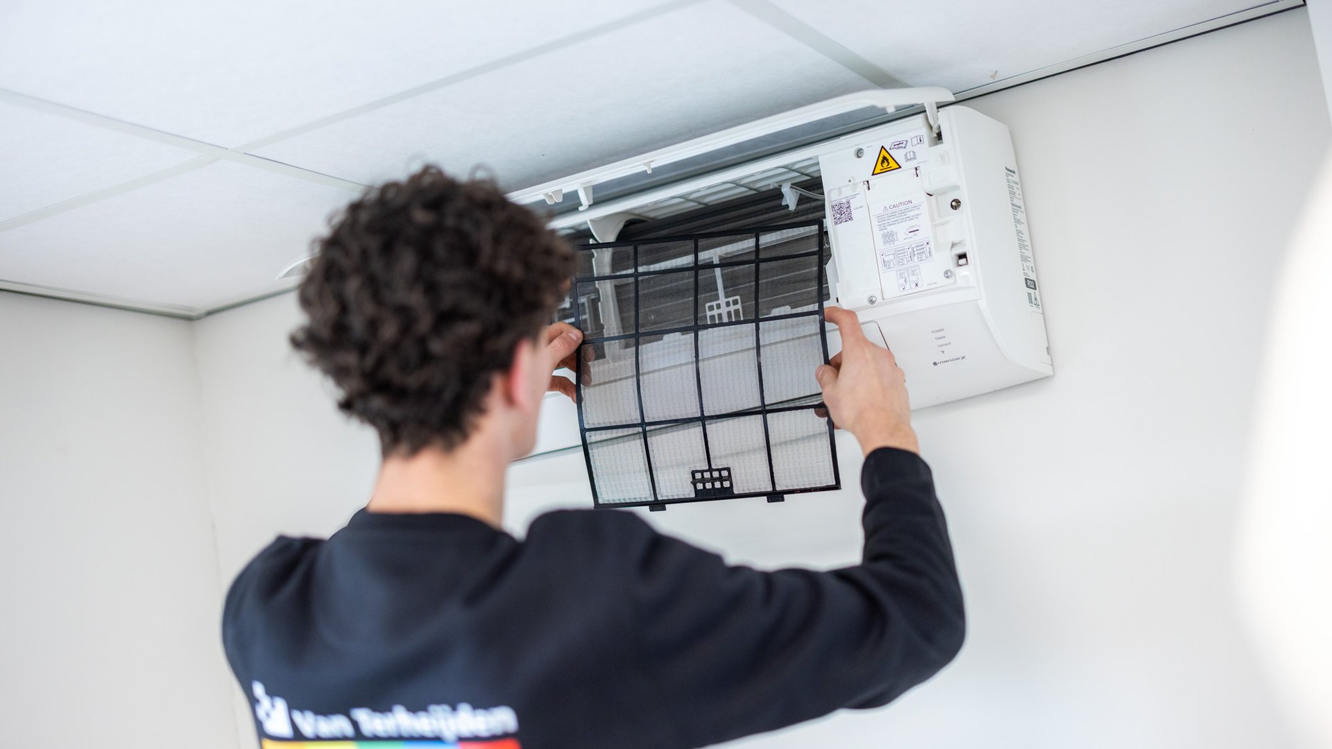 Monteur plaatst filter terug in airco na onderhoud